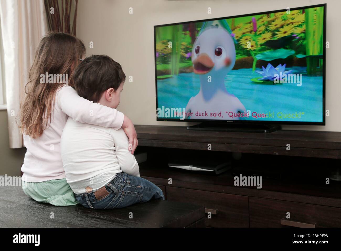 Two siblings watching cartoons on television at home Stock Photo