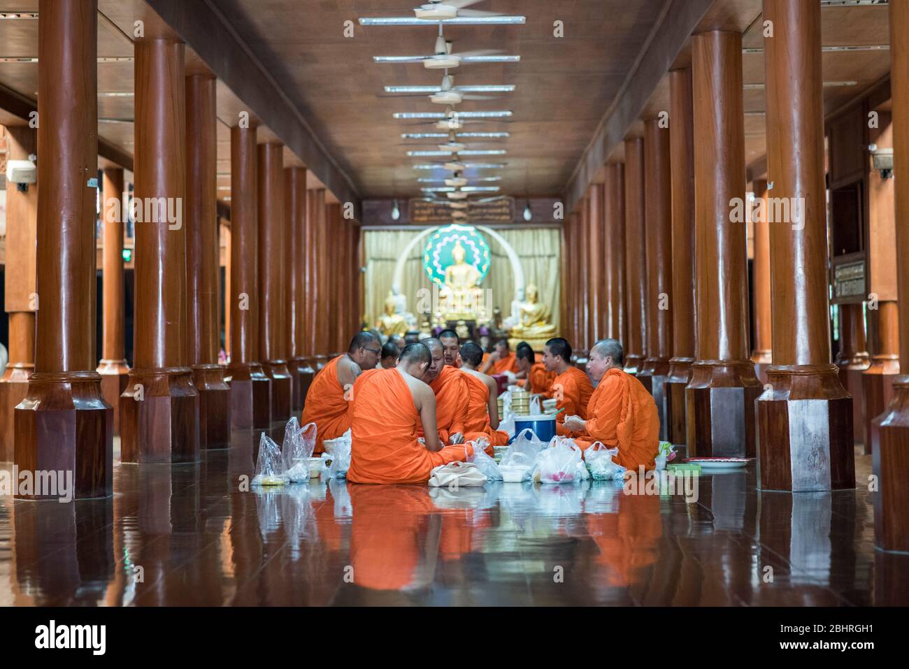 Buddhist monks eating at the Wat Pom temple Prayer hall in Samut Sakhon, Mahachai, Thailand. Stock Photo