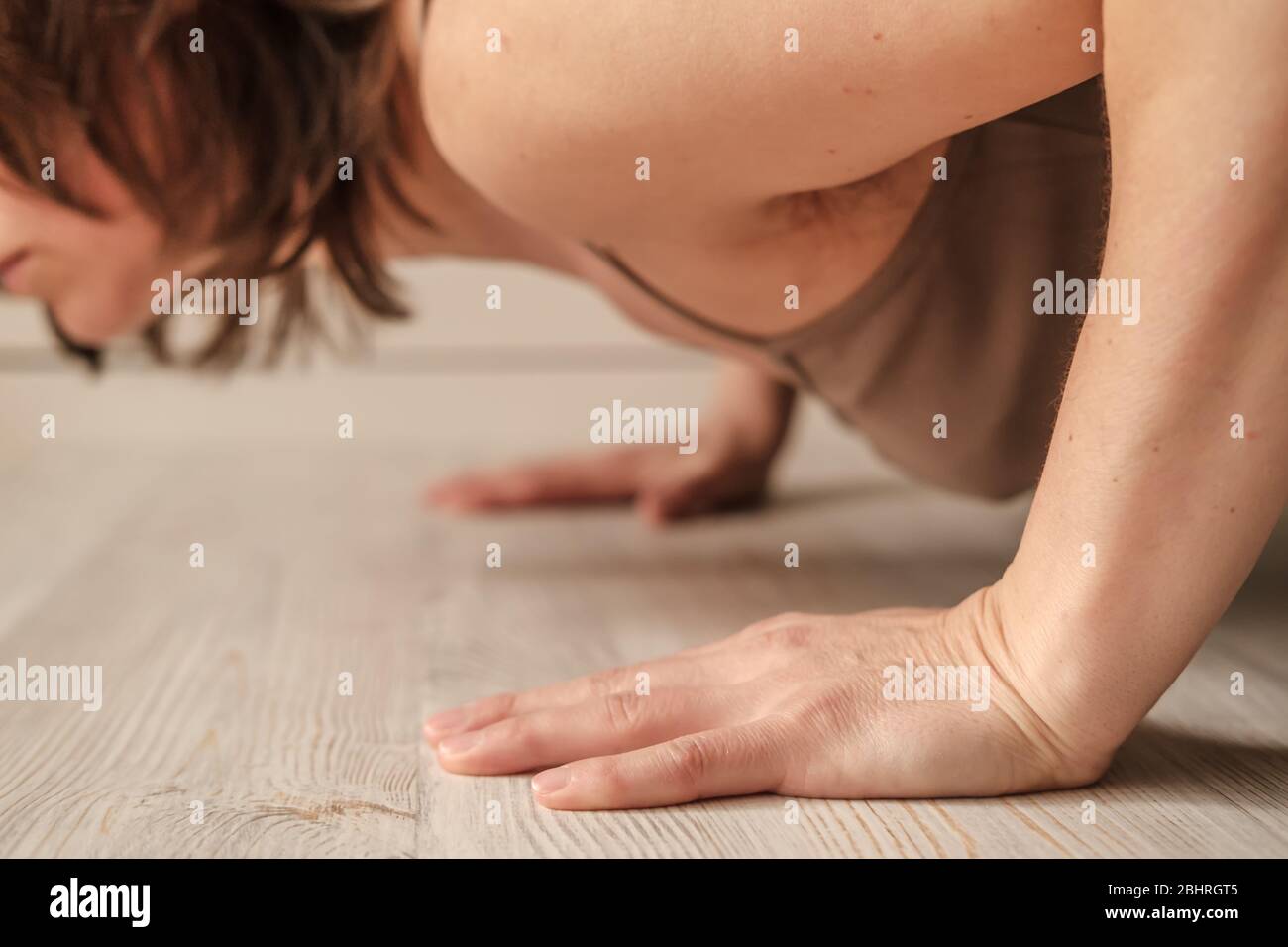 Woman doing push-ups exercise on hands or practicing yoga at home. Close-up of hands. Body positive trend. Stock Photo