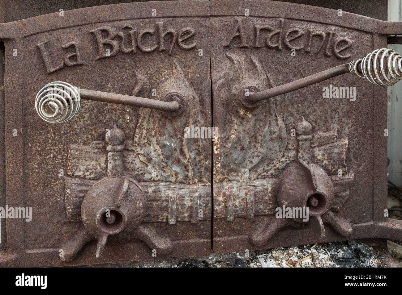 Close-up of rusted doors with silver metal handles on antique La Buche Ardene wood-burning cast, iron fireplace Stock Photo