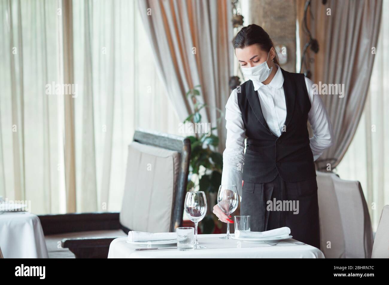 work of a waiter in a restaurant in a medical mask Stock Photo