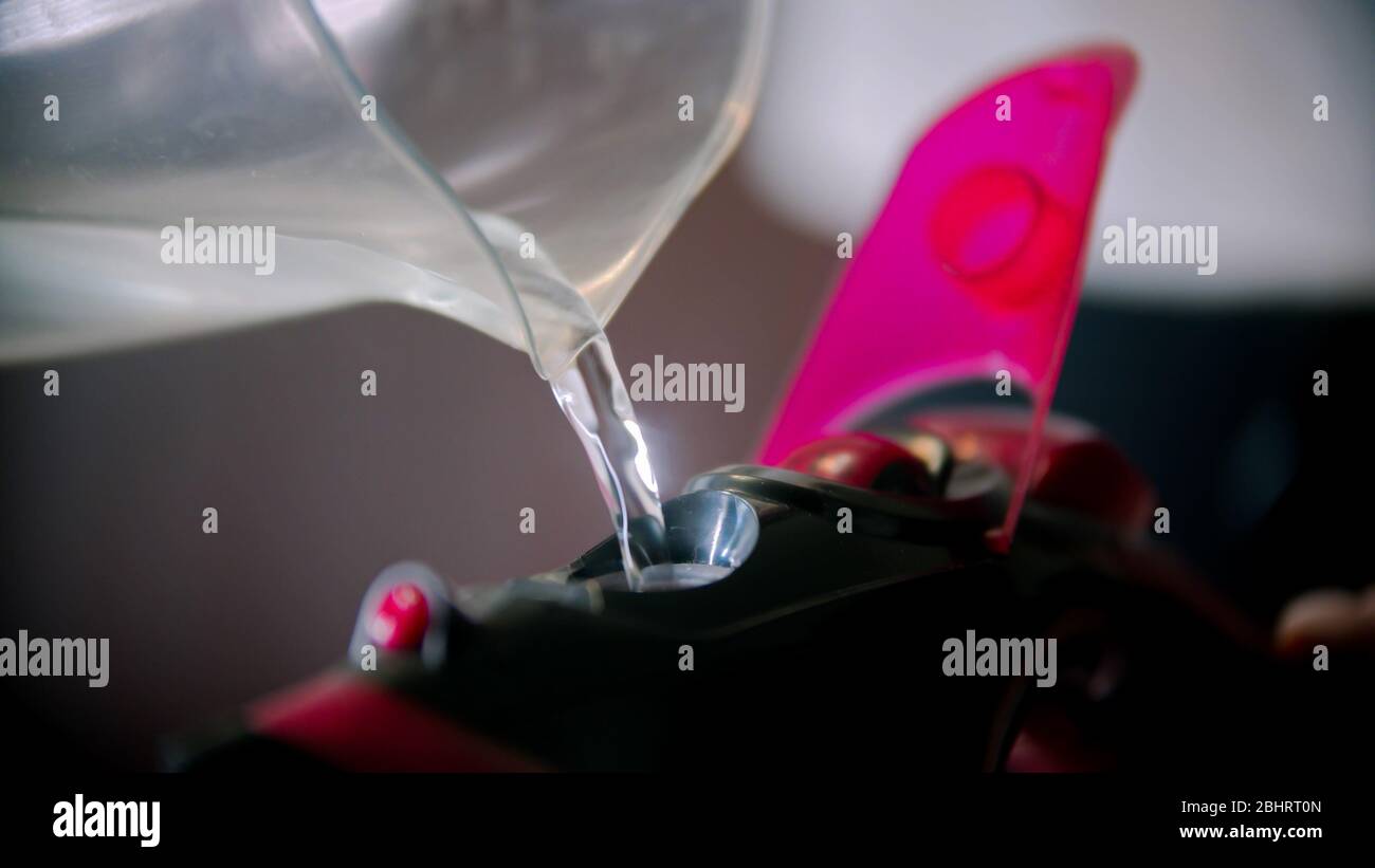 Filling an iron with water for steam ironing. Mid shot Stock Photo Alamy