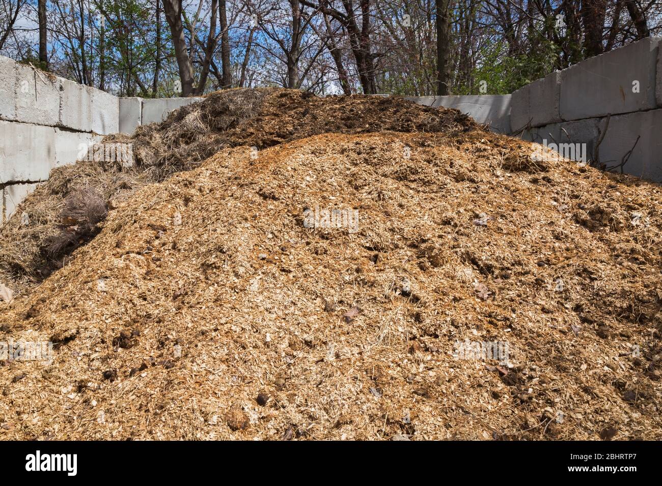 Pile of straw, leaves and woodchips composting in industrial outdoor bin Stock Photo
