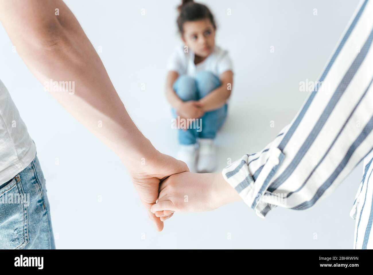 selective focus of foster parents holding hands near african american adopted daughter on white Stock Photo