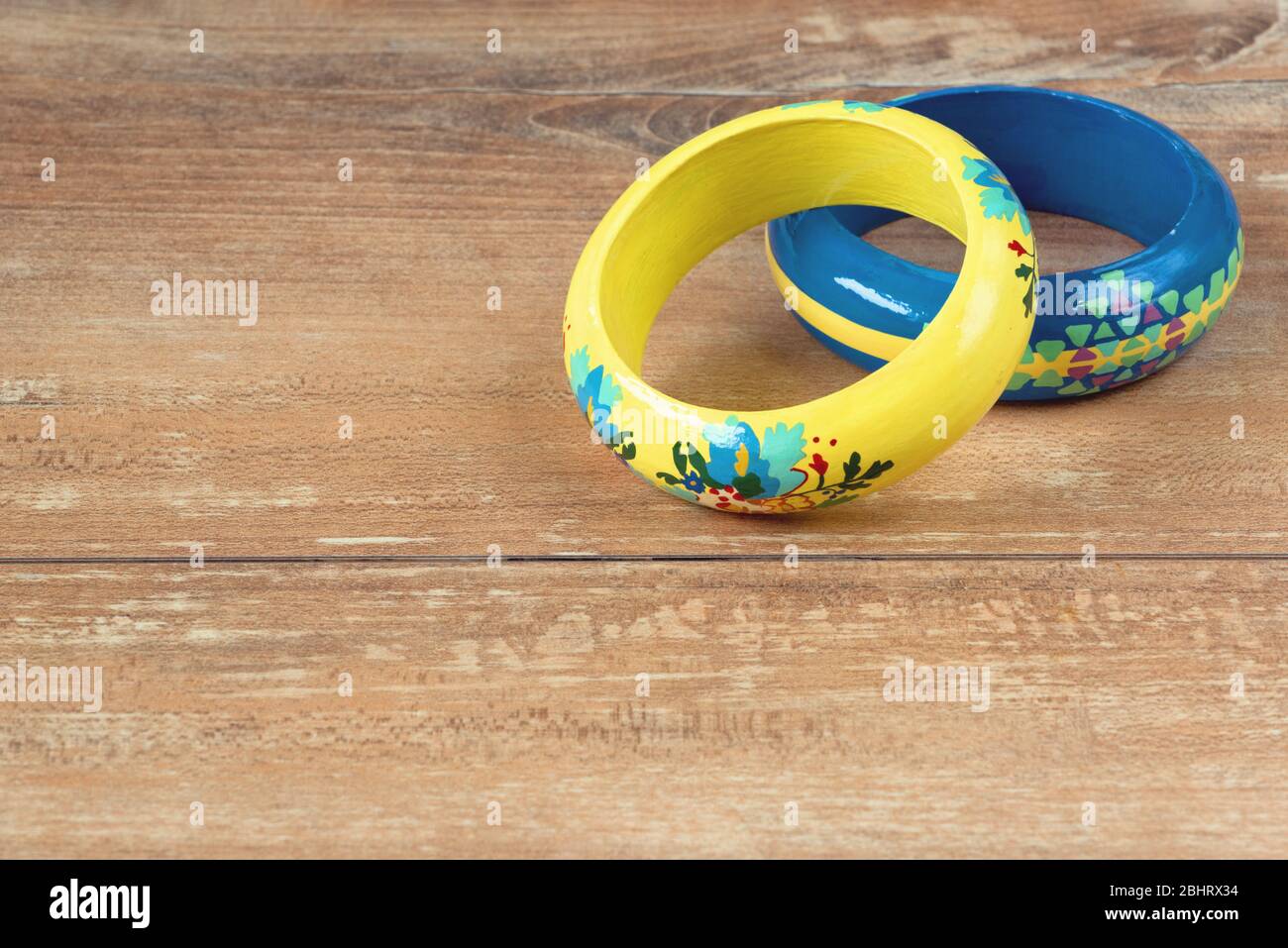Close-up image of an yellow and blue bracelets on brown wooden background. Stock Photo