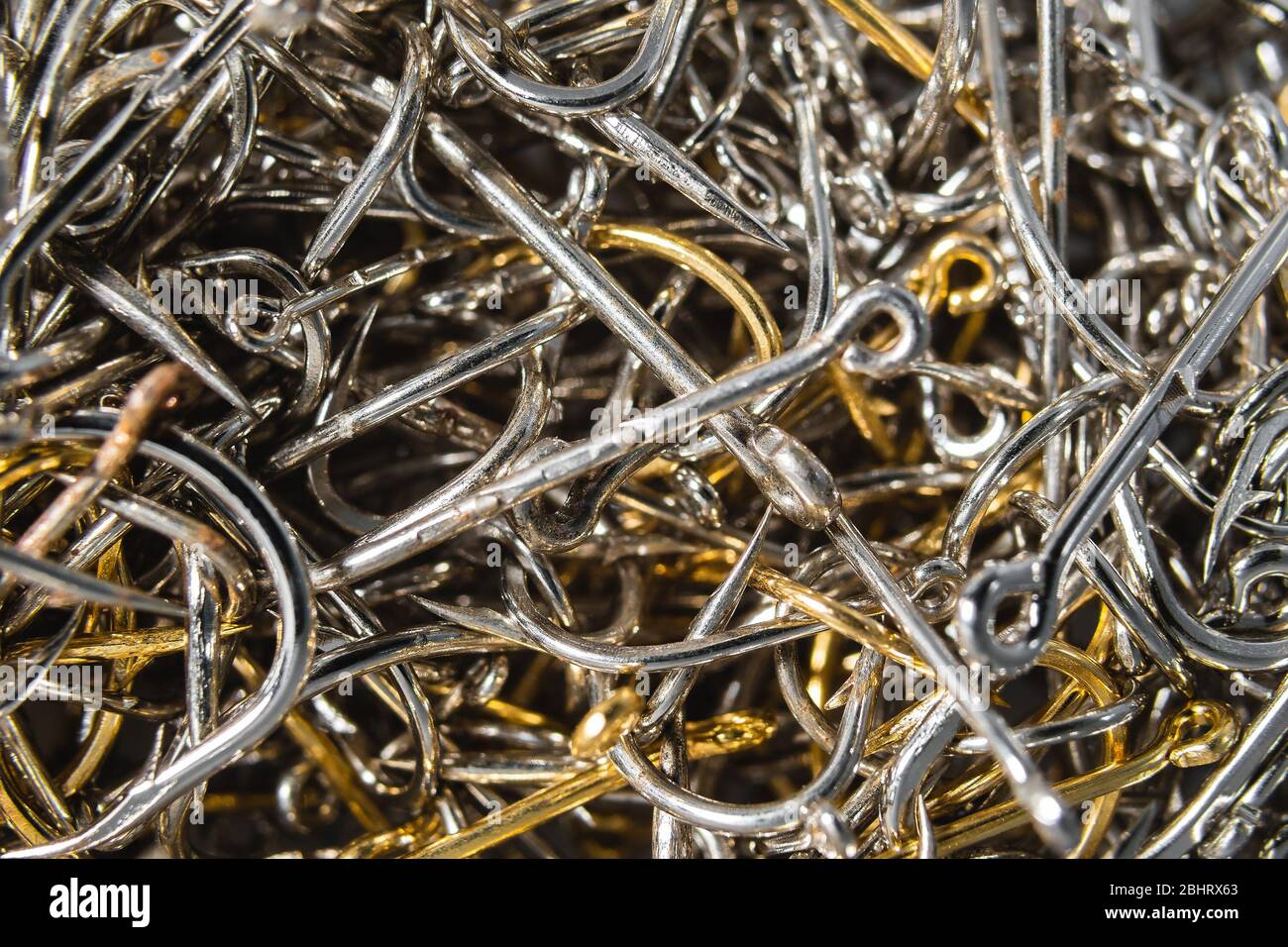 A lot of silver and gold fishing hooks. Fishing hook background. Stock Photo