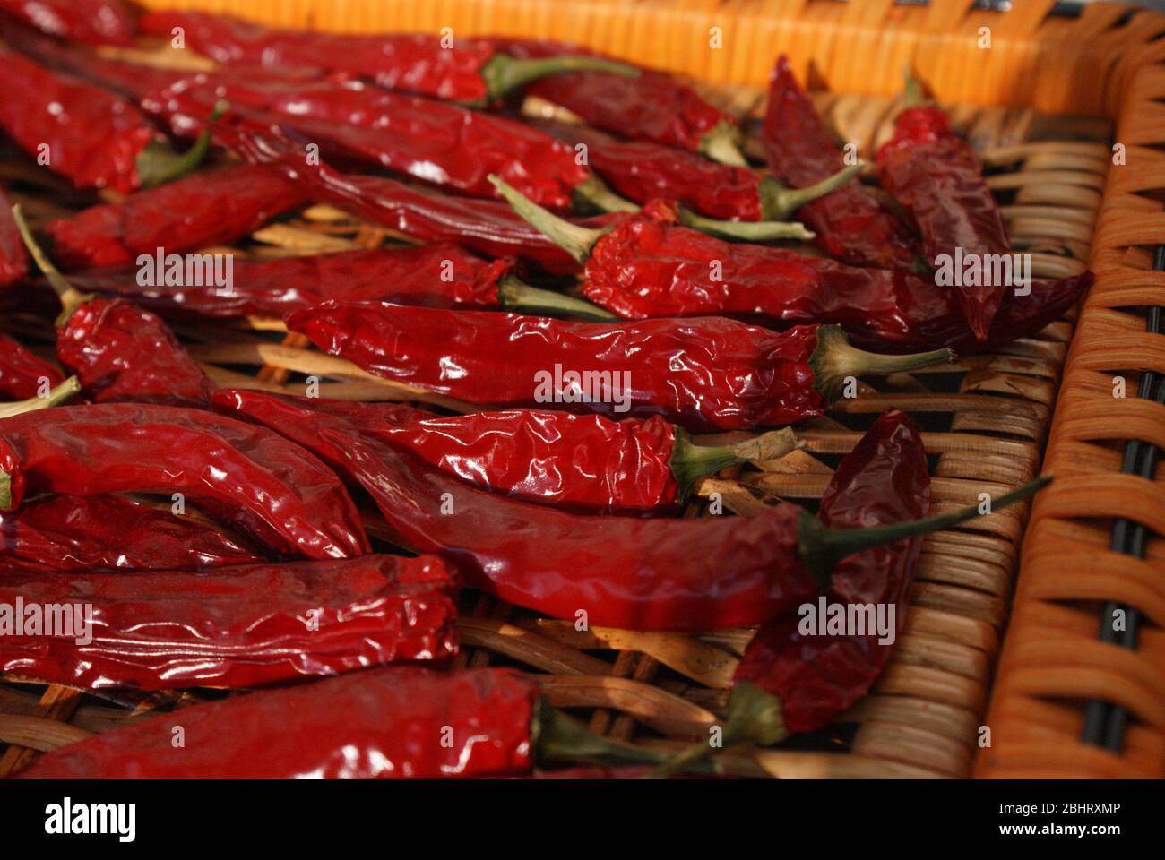 Red hot chili peppers drying in the sun on a wicker basket tray Stock Photo