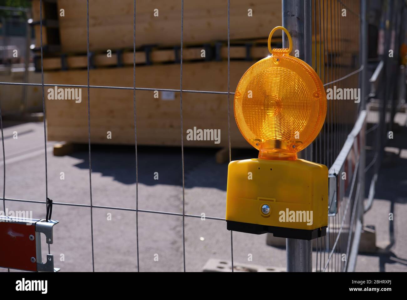 Construction site, yellow warning lamp on a construction fence in front