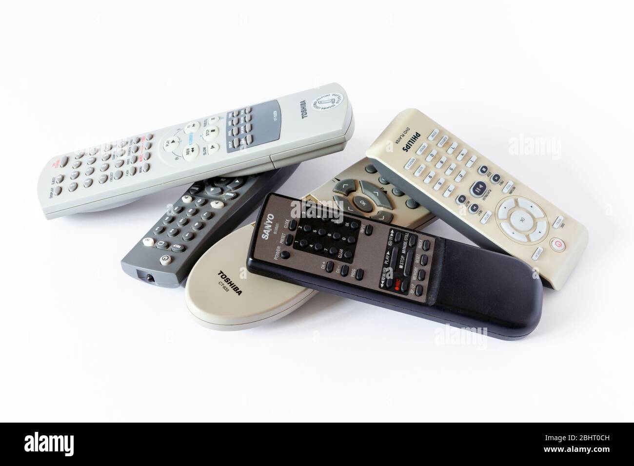 An assortment of old TV and video remote controls piled up on a white background Stock Photo