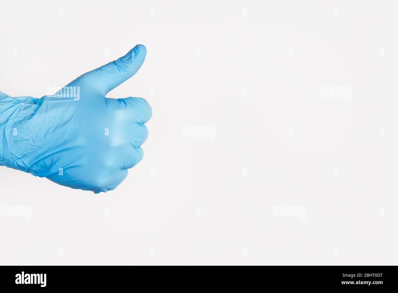 Hand In Medical Glove Showing Thumb Up On white Background. Copy space Stock Photo