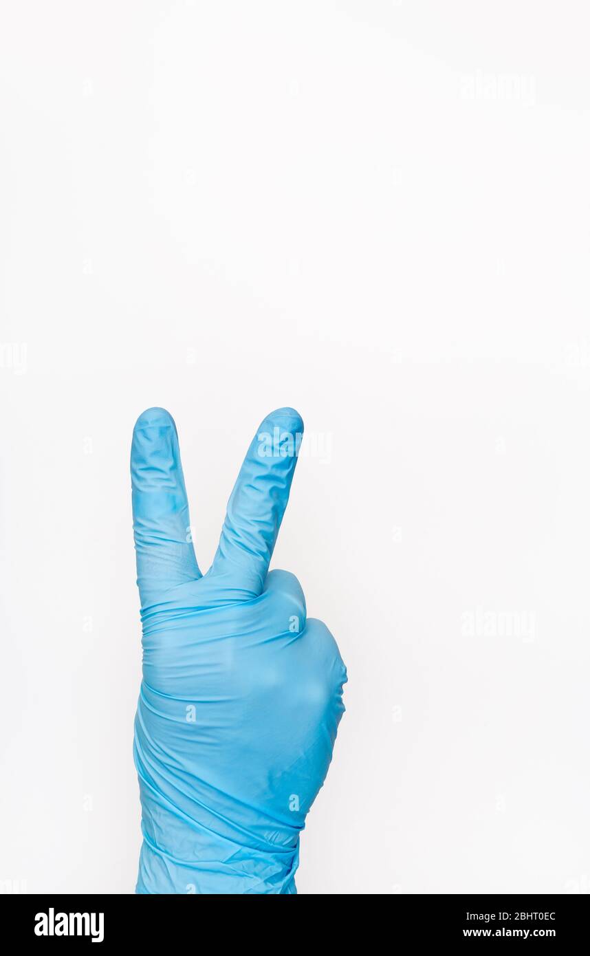 Hand In Medical Glove showing victory sign on white background. Gesture of victory. Copy space Stock Photo