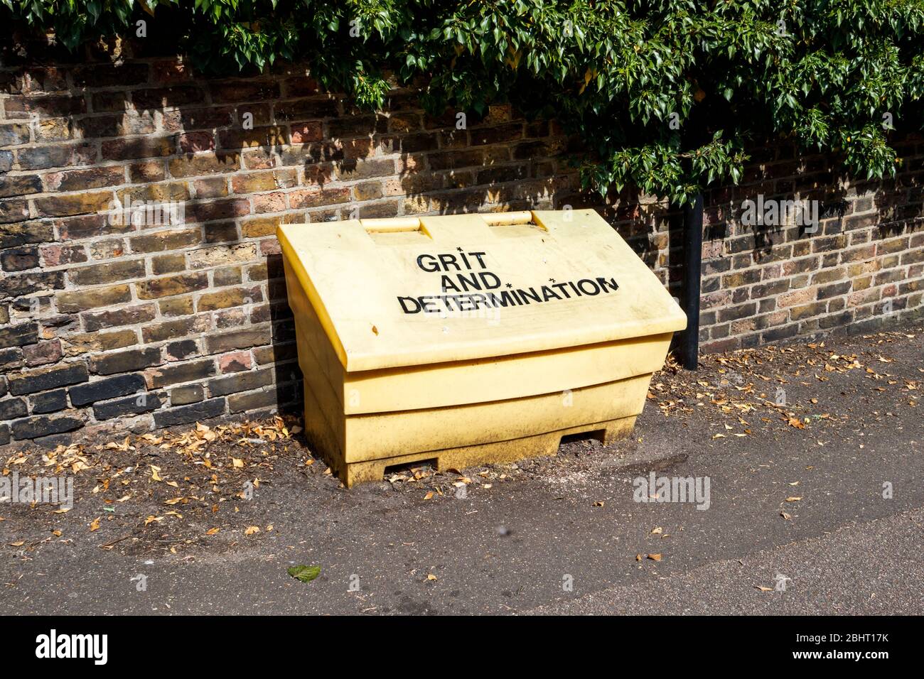 A yellow council roadside grit box labelled 'Grit and Determination' in