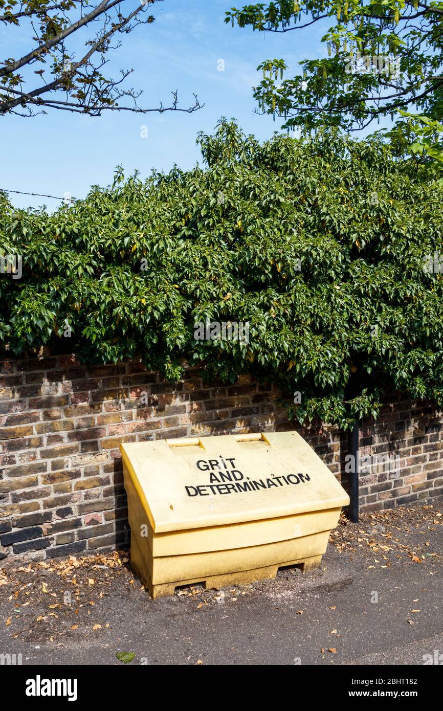 A yellow council roadside grit box labelled 'Grit and Determination' in Haringey, North London, UK, during the coronavirus pandemic lockdown Stock Photo