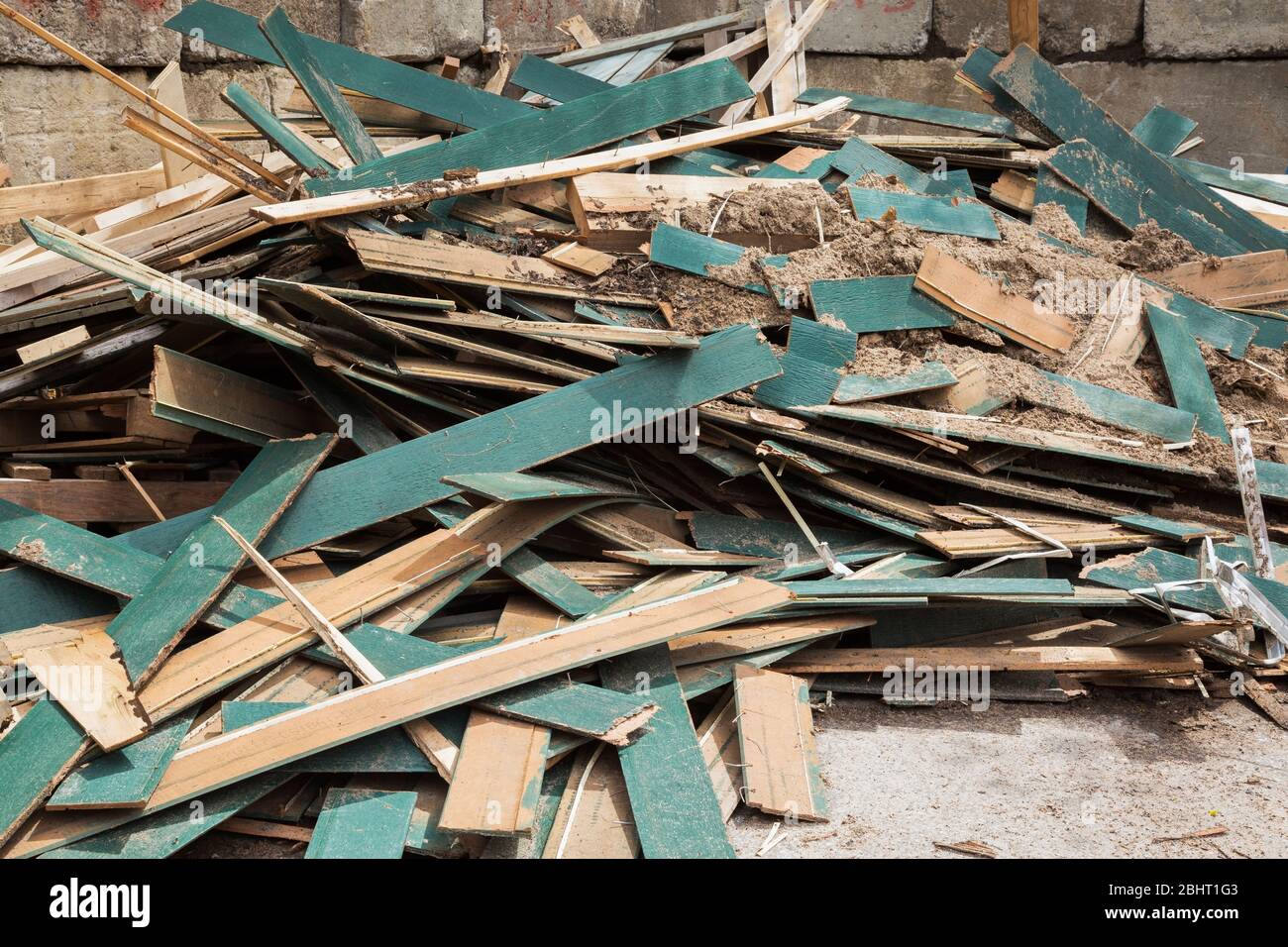 Pile of discarded green wooden planks in industrial outdoor trash bin Stock Photo
