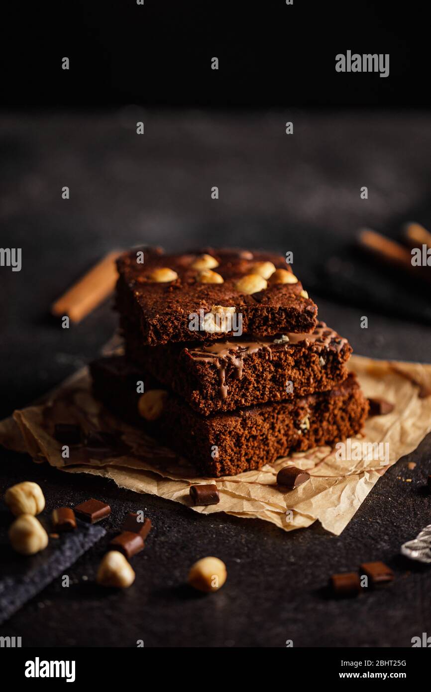 Dark chocolate and cocoa brownie cake on light gray concrete table, pieces of chocolate and hazelnut Stock Photo