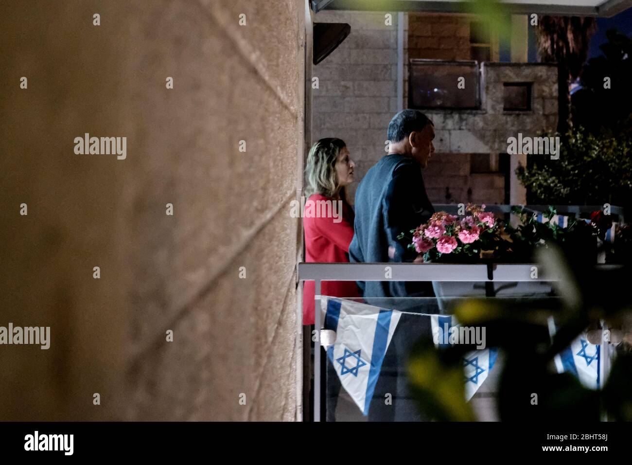 Jerusalem, Israel. 27th Apr, 2020. Israelis take to their balconies to sing the Hatikva, the Israeli National Anthem, at the conclusion of a ceremony marking the beginning of Memorial Day, conducted at the Western Wall without an audience and broadcast live, nationwide, on television. The government has imposed a total lockdown on Memorial Day and the following Independence Day in an attempt to further curb COVID-19 spread. Credit: Nir Alon/Alamy Live News Stock Photo