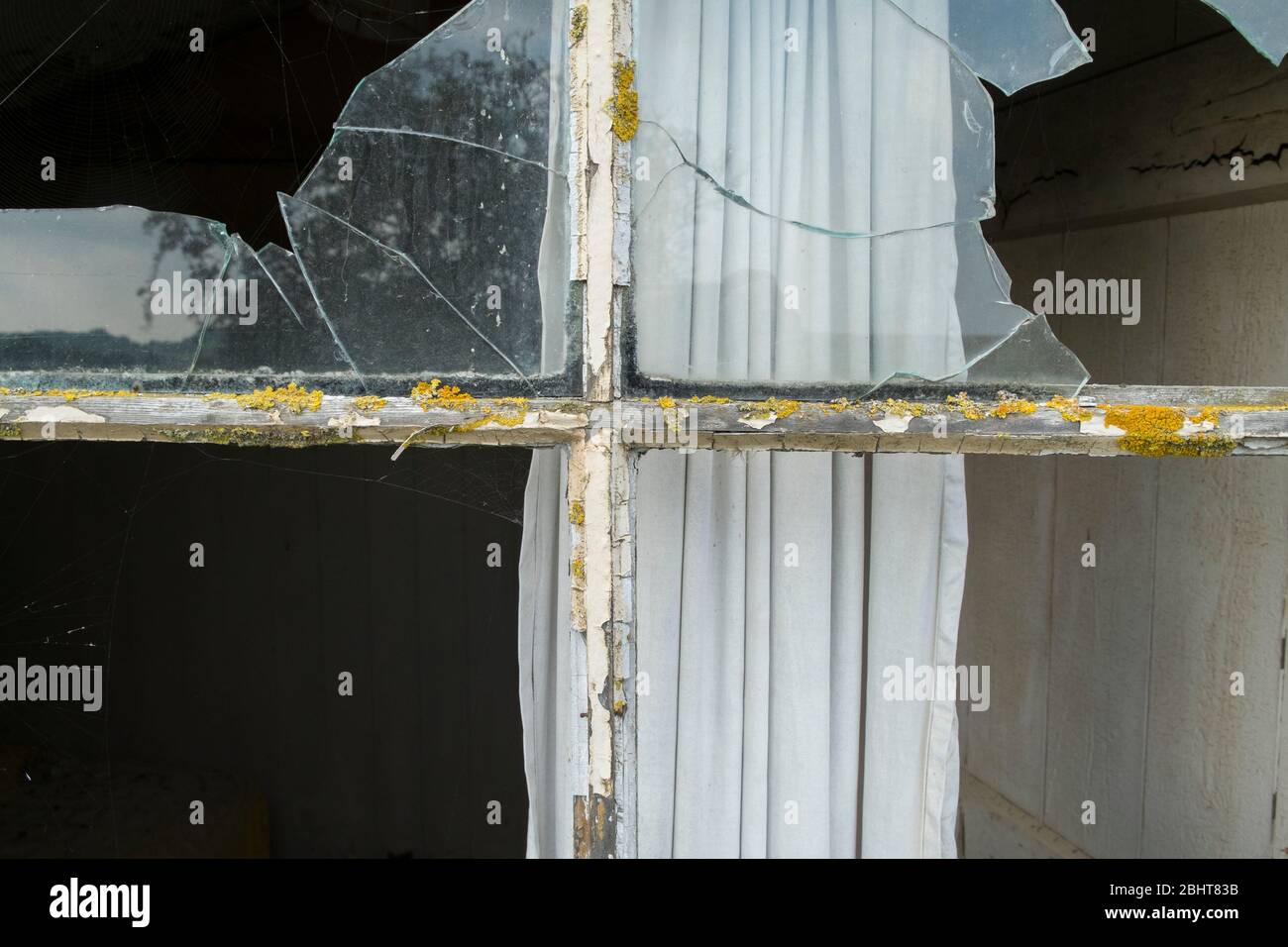 Derelict dwelling with broken window pane. Stock Photo