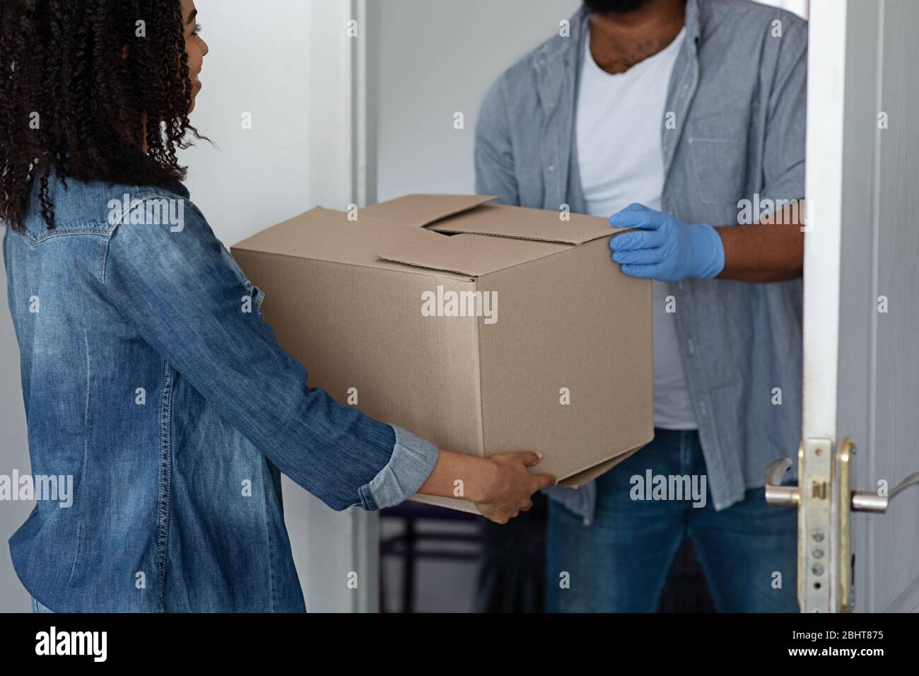 Unrecognizable Black Delivery Man Delivering Package To Woman Homeowner Stock Photo