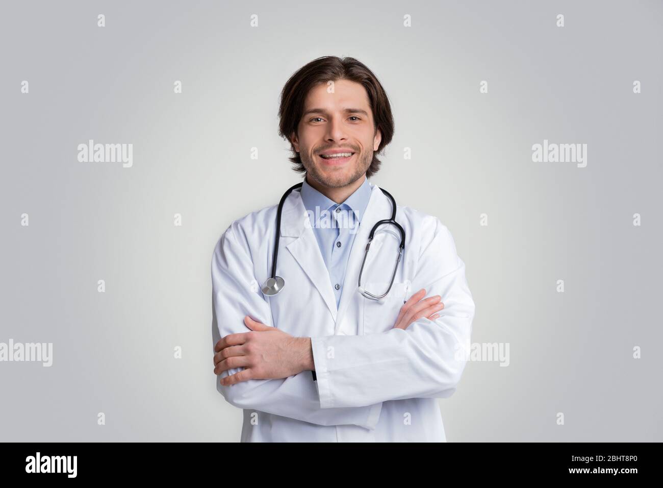 Smiling Medical Specialist Posing With Folded Arms Over White Background Stock Photo