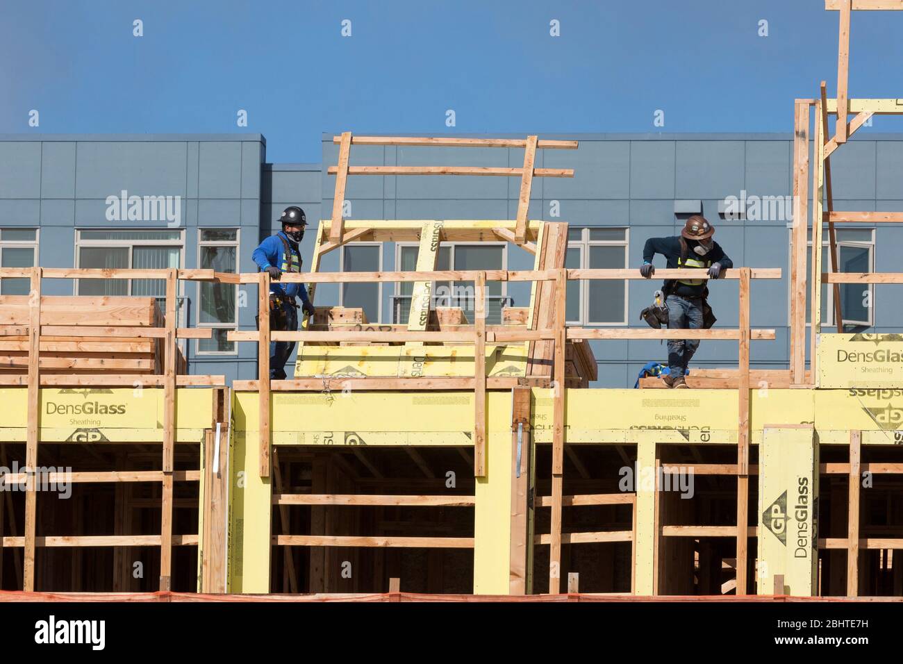 Workers wear face masks at a building site in West Seattle as construction resumes on Monday, April 27, 2020. Low-risk residential and commercial construction projects must comply with COVID-19 worksite-specific safety practices to resume. Stock Photo