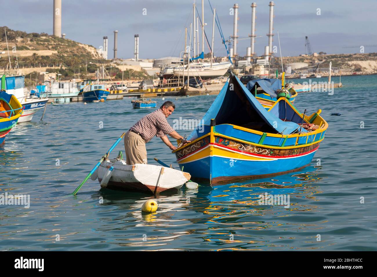 Man tending traditional luzzo fishing boat, Marsaxlokk, Malta Stock Photo
