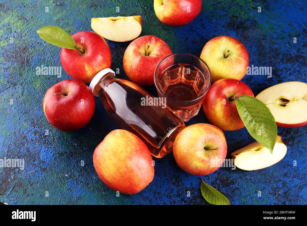 Apple cider drink and apples with leaves on rustic table Stock Photo