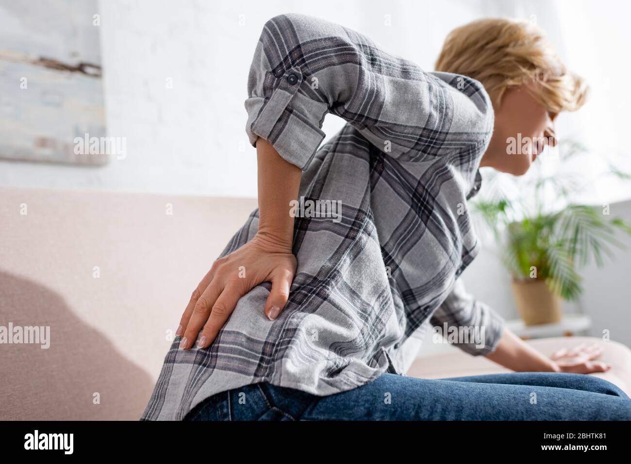 selective focus of mature woman suffering from back pain while sitting ...
