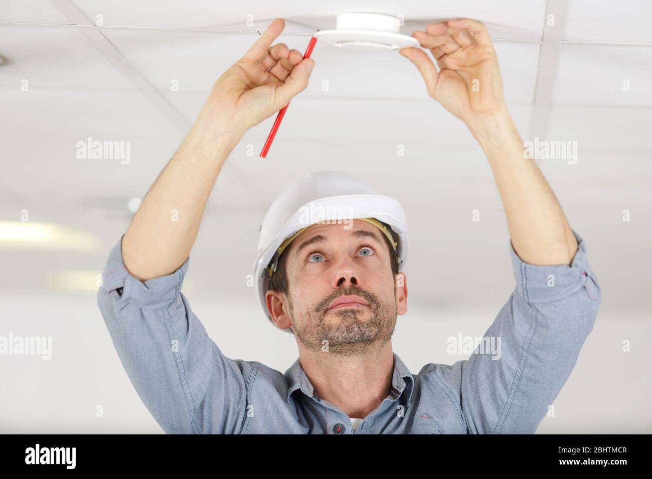 man installing smoke or carbon monoxide detector Stock Photo