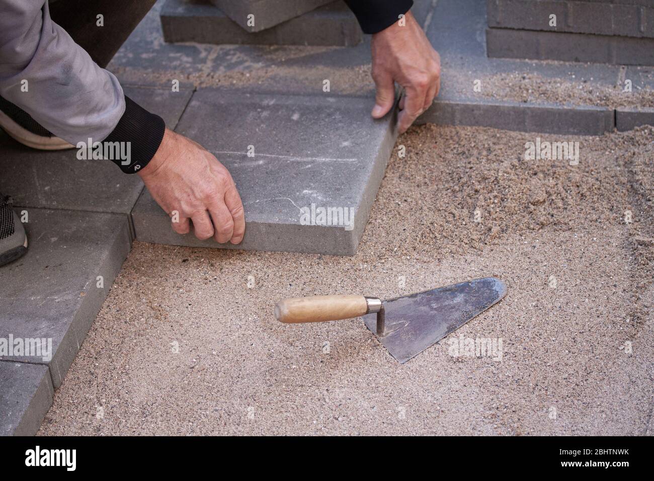 Hands of a man laying pavers or tiles in sand Stock Photo Alamy
