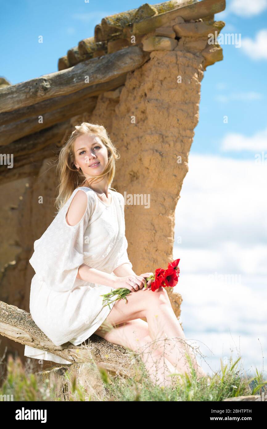 Beautiful woman wearing white dress sitting with poppies flowers in ...