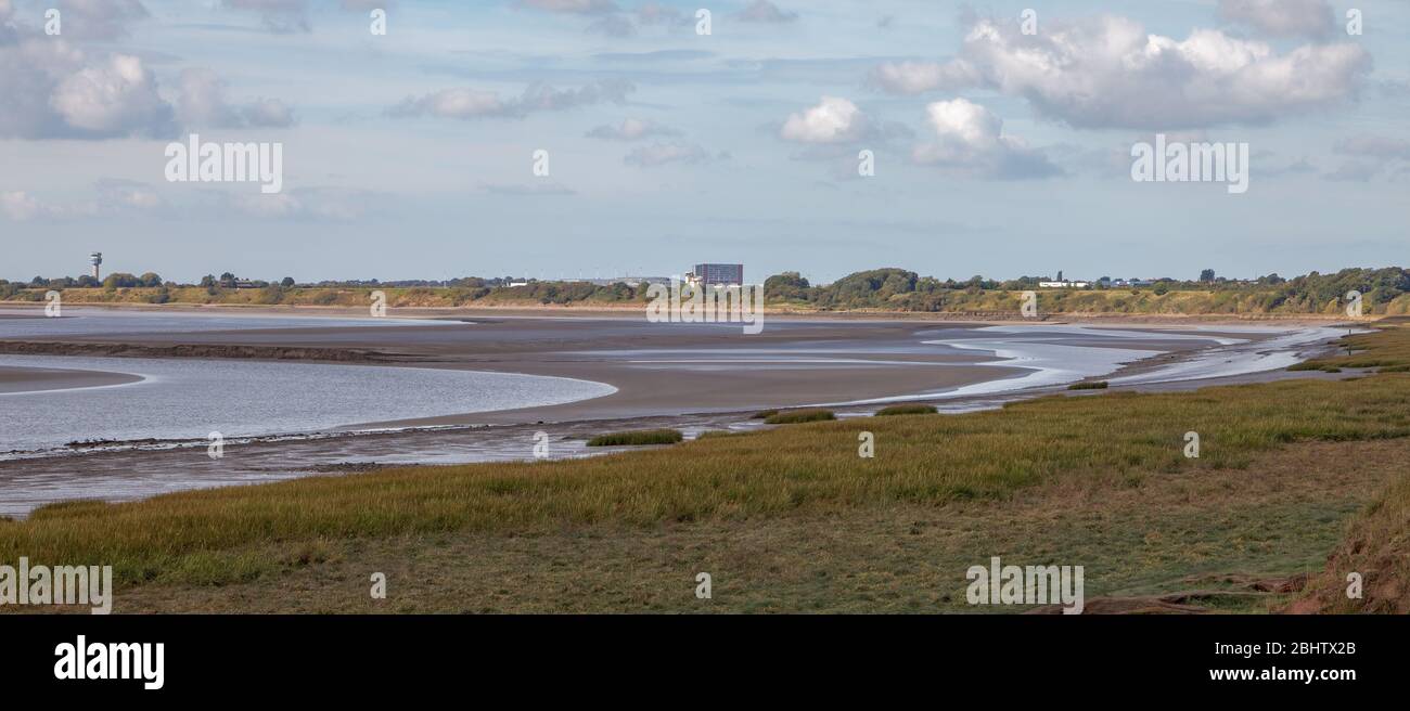 Mudflats and saltmarsh near Hale Head on the Mersey Estuary, with the control tower of Liverpool John Lennon Airport in the background Stock Photo