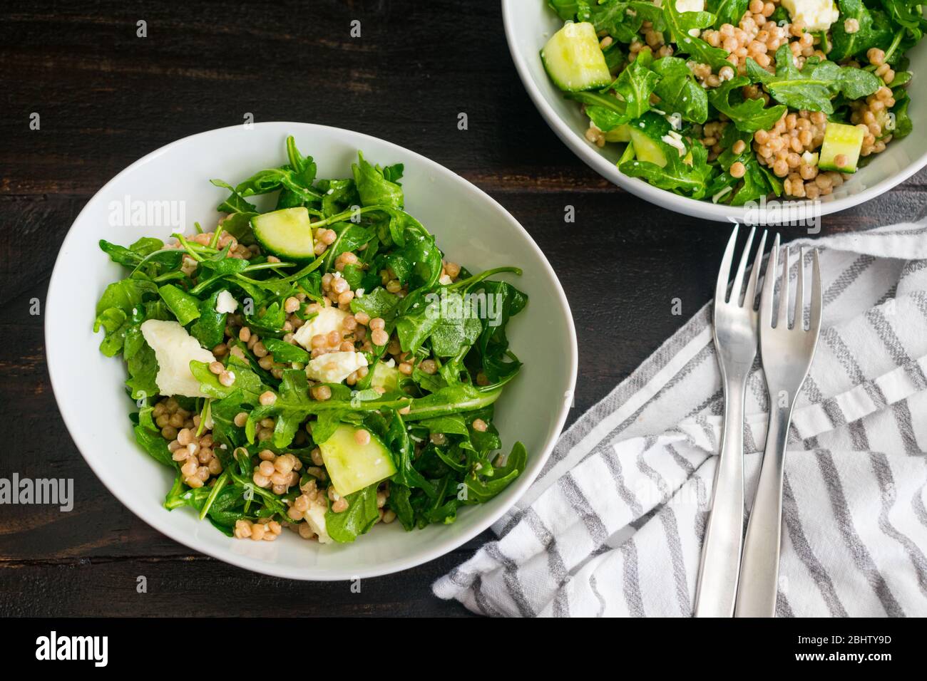 Lemony Arugula Salad with Couscous, Cucumbers, and Feta: Arugula salad with chunks of cucumber, feta cheese crumbles, and whole wheat pearl couscous Stock Photo