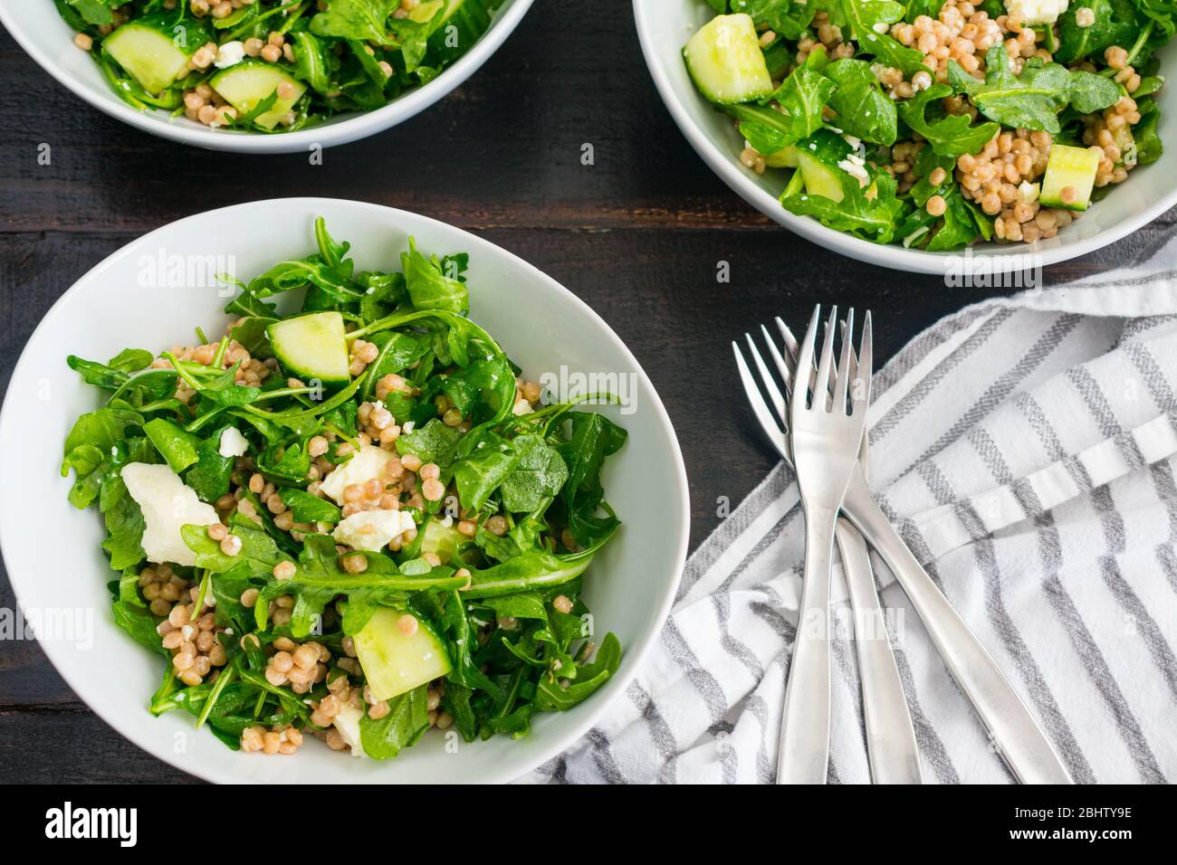 Lemony Arugula Salad with Couscous, Cucumbers, and Feta: Arugula salad with chunks of cucumber, feta cheese crumbles, and whole wheat pearl couscous Stock Photo