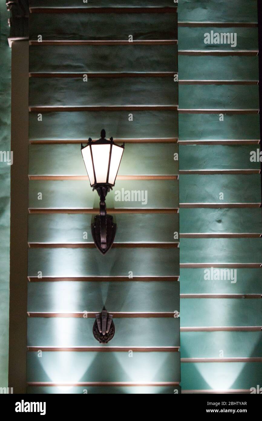 The design element is an old-style glowing lantern on the wall of the building. Street lighting. Retro. Vertical photo Stock Photo