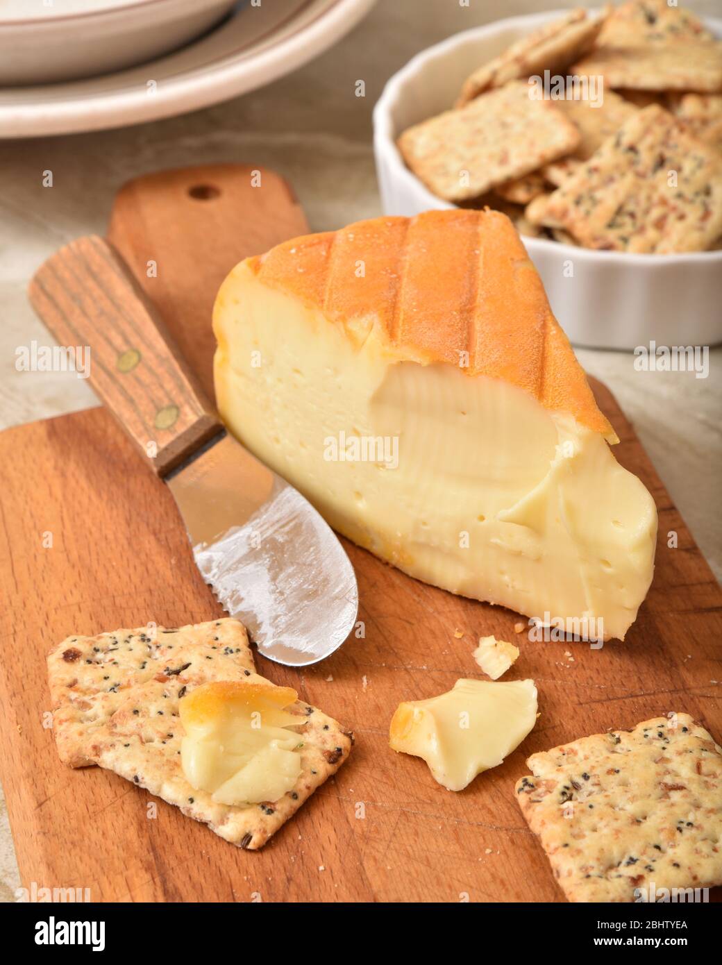 A wedge of imported Belgium cheese with whole grain artisan crackers Stock Photo
