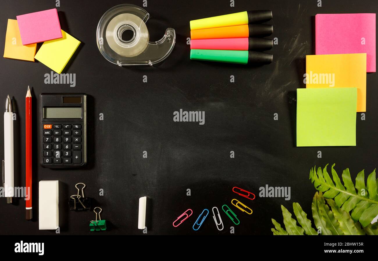 school stationary supplies on black chalkboard background with copy space ready for graphic design, school education learning concept, calculator, pen Stock Photo