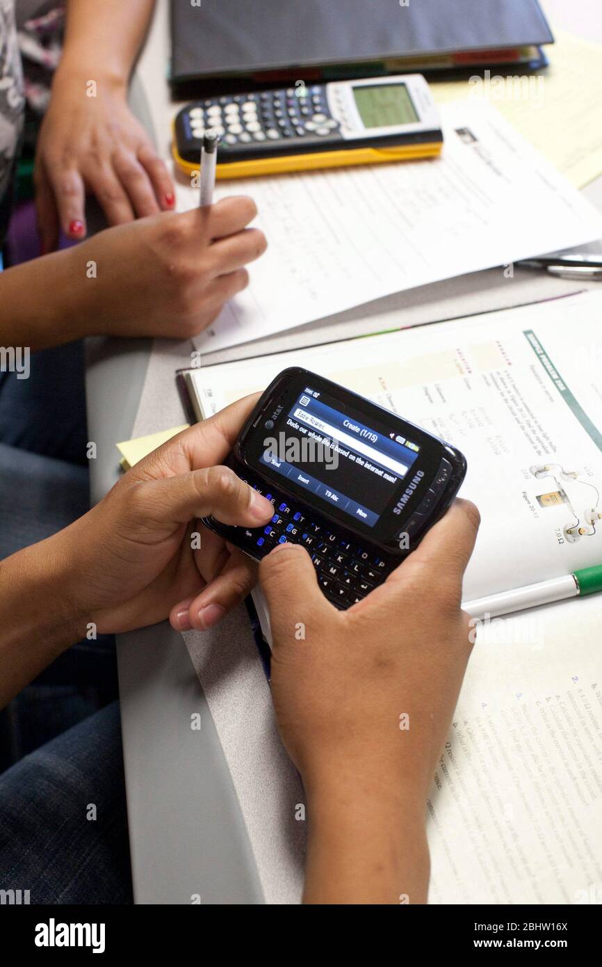 El Paso, Texas USA, May 2010: Student uses thumbs to type text message on a cell phone during class at  Mission Early College High School.  ©Bob Daemmrich Stock Photo