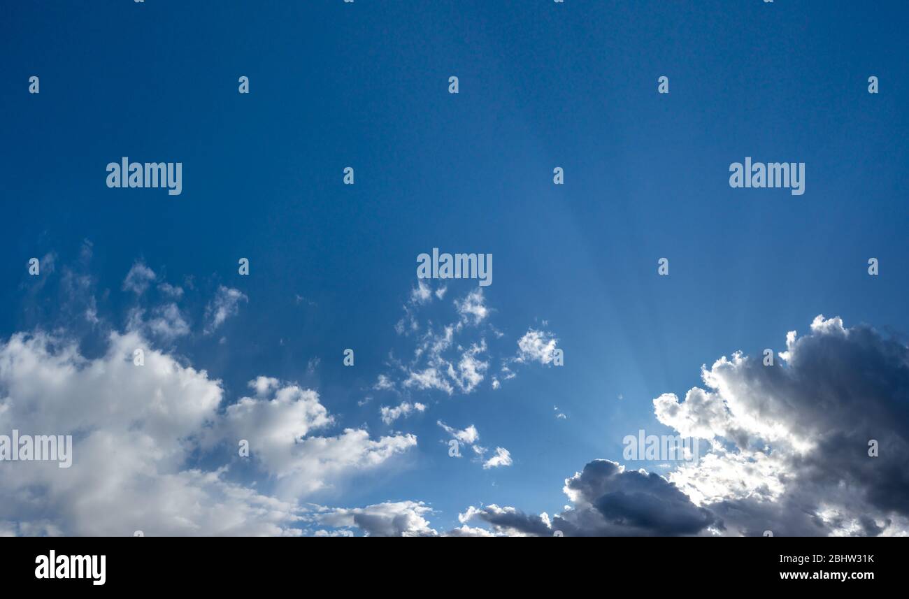 Scenic cloudy blue sky panorama with blank space for text. Sunlight rays in high large dramatic cloudscape moody background Stock Photo