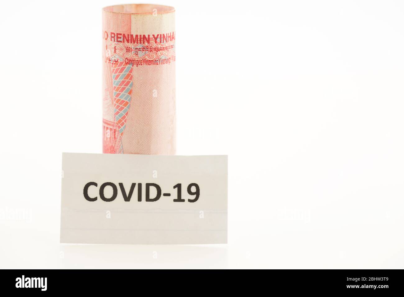 Chinese currency placed with lettered Covid-19 card reflects impact of coronavirus on China's economy and finance. Stock Photo