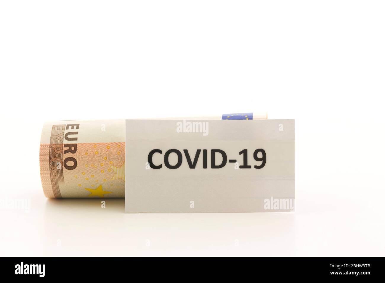 Covid-19 lettered on card placed in front of fallen Euro currency reflects economic impact of coronavirus crisis Stock Photo