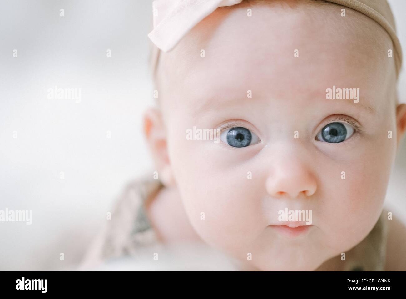 Closeup of blue eyed baby girl looking at camera Stock Photo