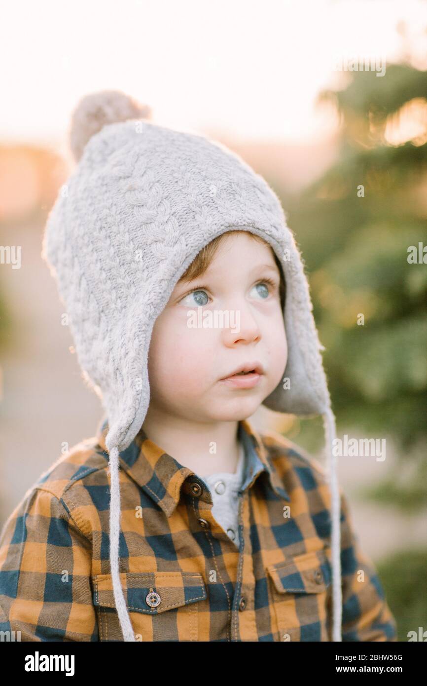 Toddler wearing winter hat looks up magical, holiday, thoughtful Stock