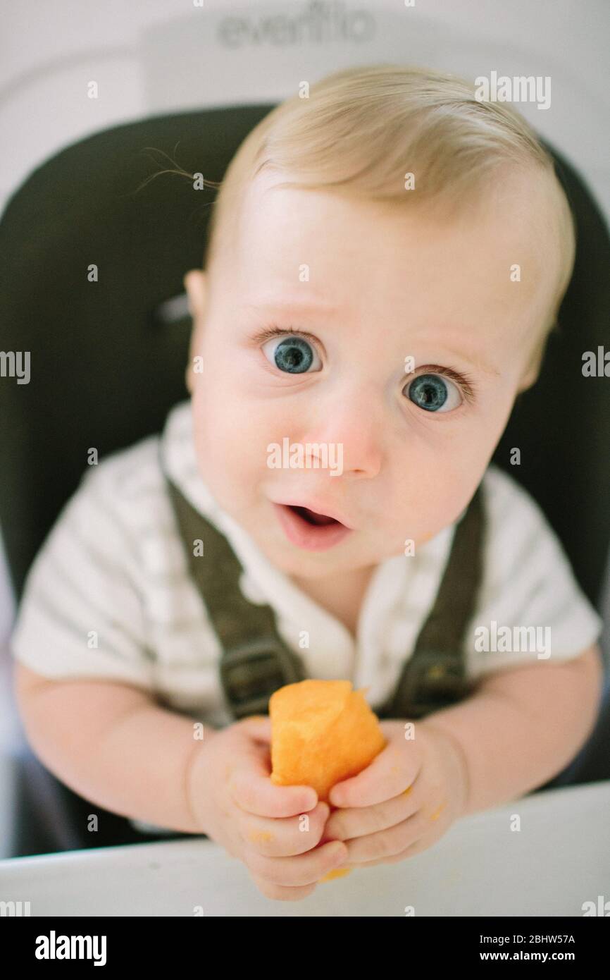Baby making a funny expression as he tries a new food Stock Photo