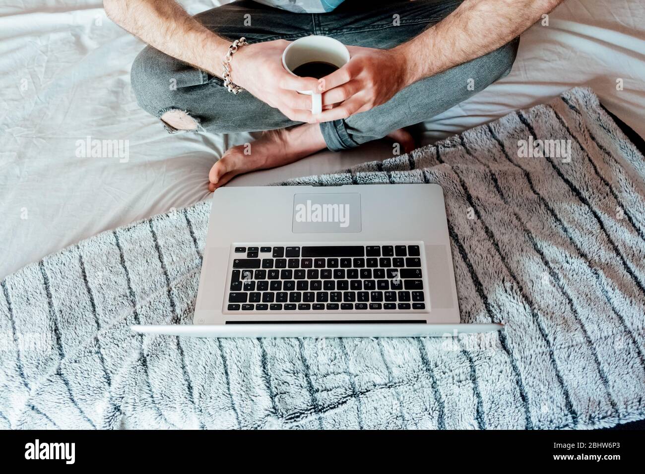 Man drinking coffee while working from bed in Madrid.Spain. Stock Photo