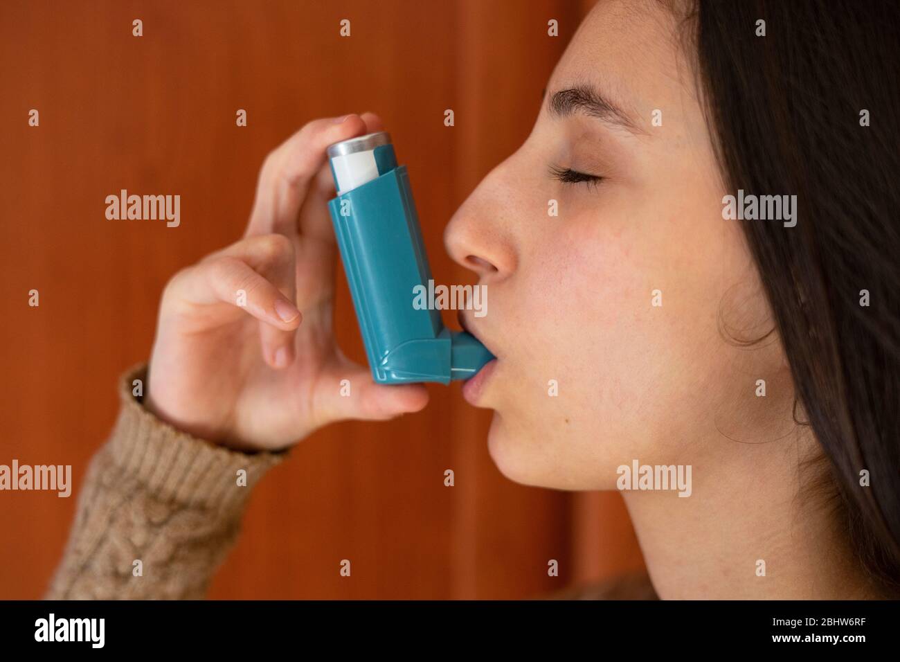Woman inhaling the blue asthma inhaler. Asthma inhaler Concept Stock