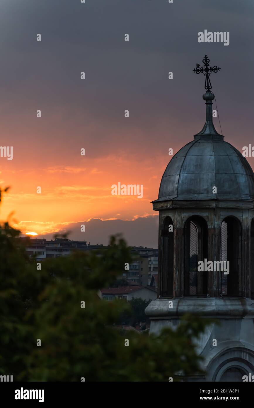 Red/ orange sunset over a town and orthodox church Stock Photo