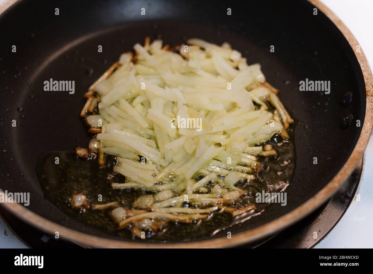 Fresh shredded, hashbrown potatoes frying in a pan with oil on the