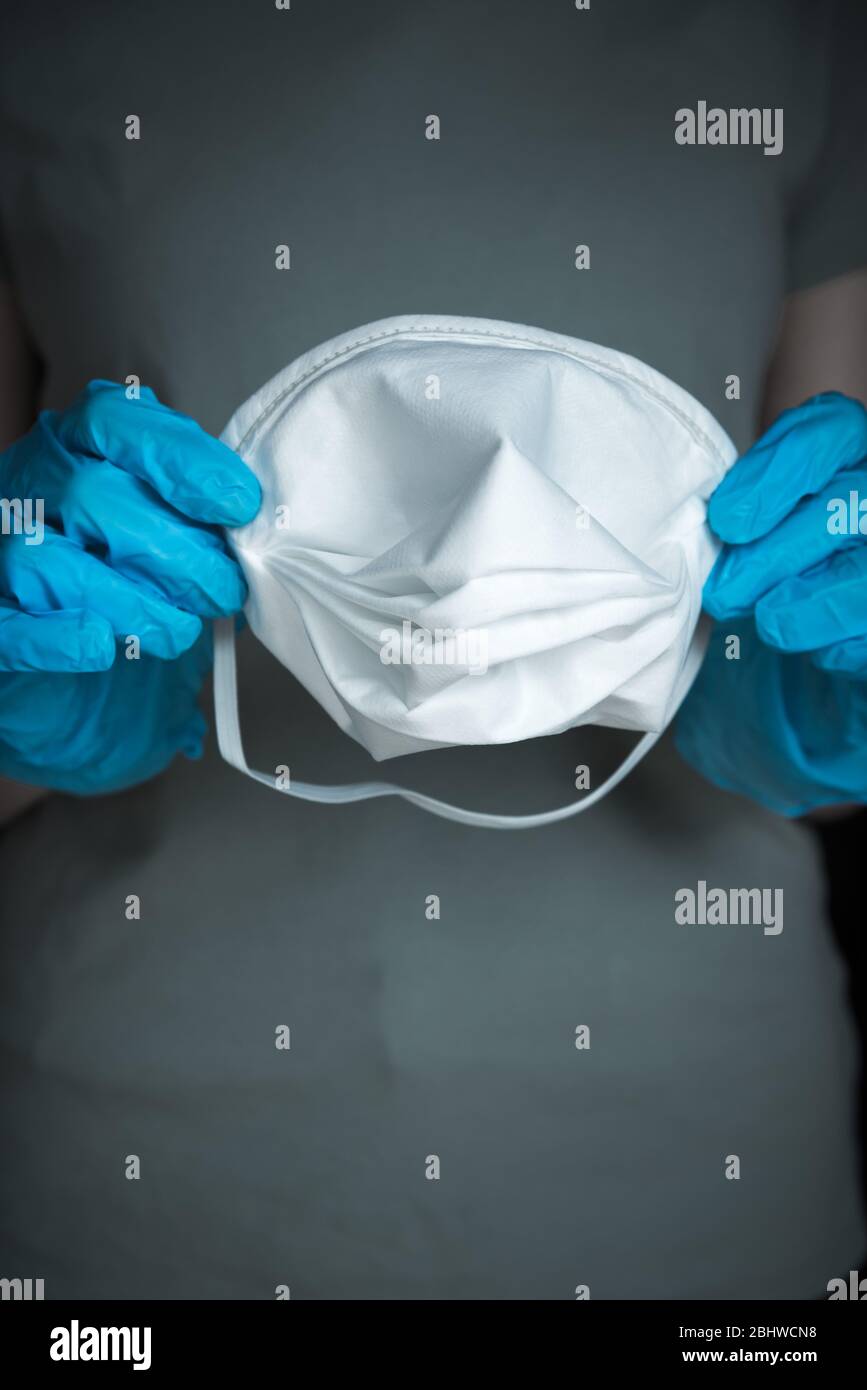 Woman wearing blue surgical gloves and holding medical N95 mask Stock Photo Alamy