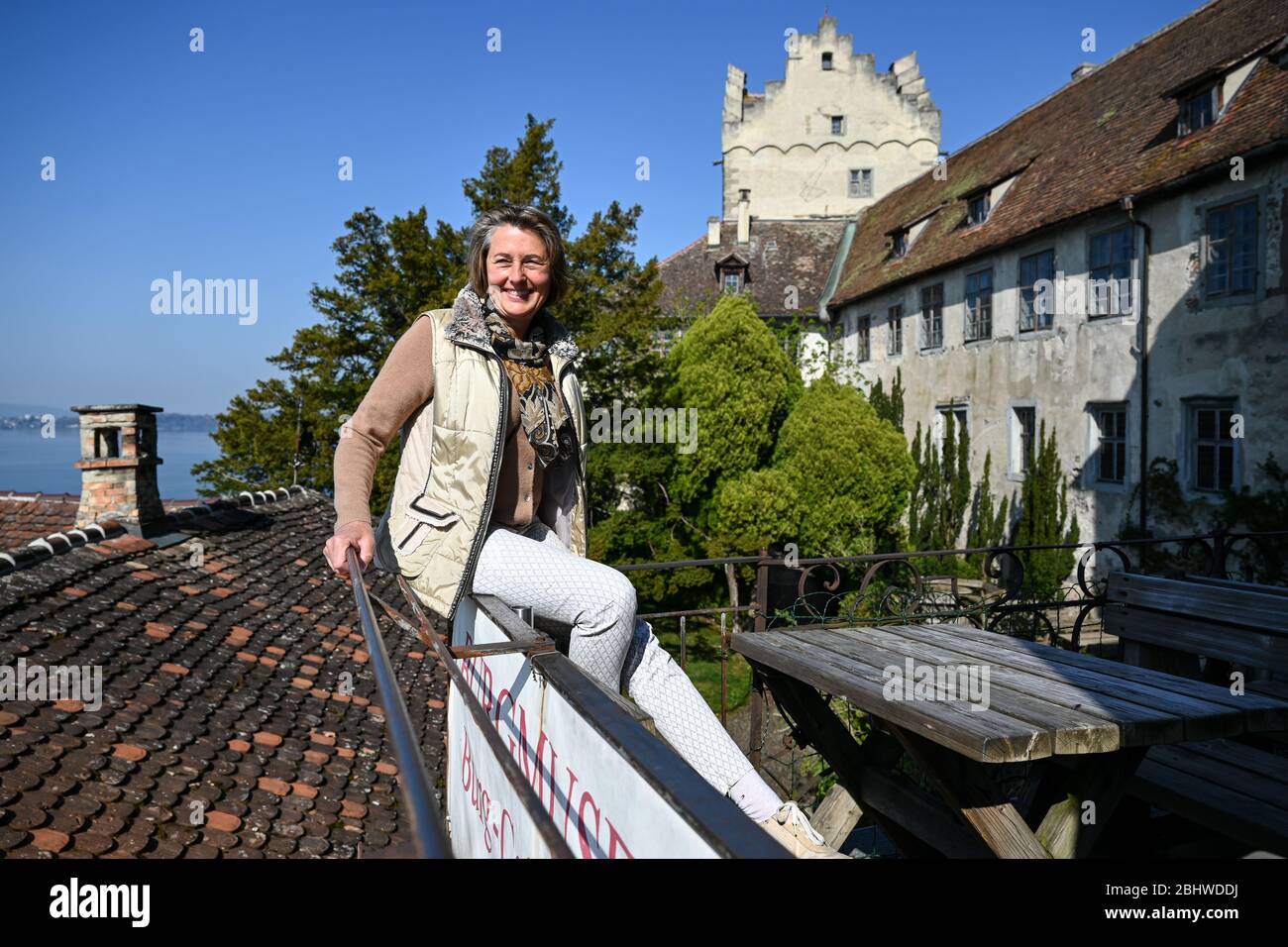 Meersburg, Germany. 08th Apr, 2020. Lady Julia Naeßl-Dom sits on the railing of the castle café of Meersburg Castle. The castle is considered one of the oldest inhabited castles in Germany. (Photo taken with drone. To dpa: ''Existence-threatening' - castles and palaces suffer from corona crisis') Credit: Felix Kästle/dpa/Alamy Live News Stock Photo