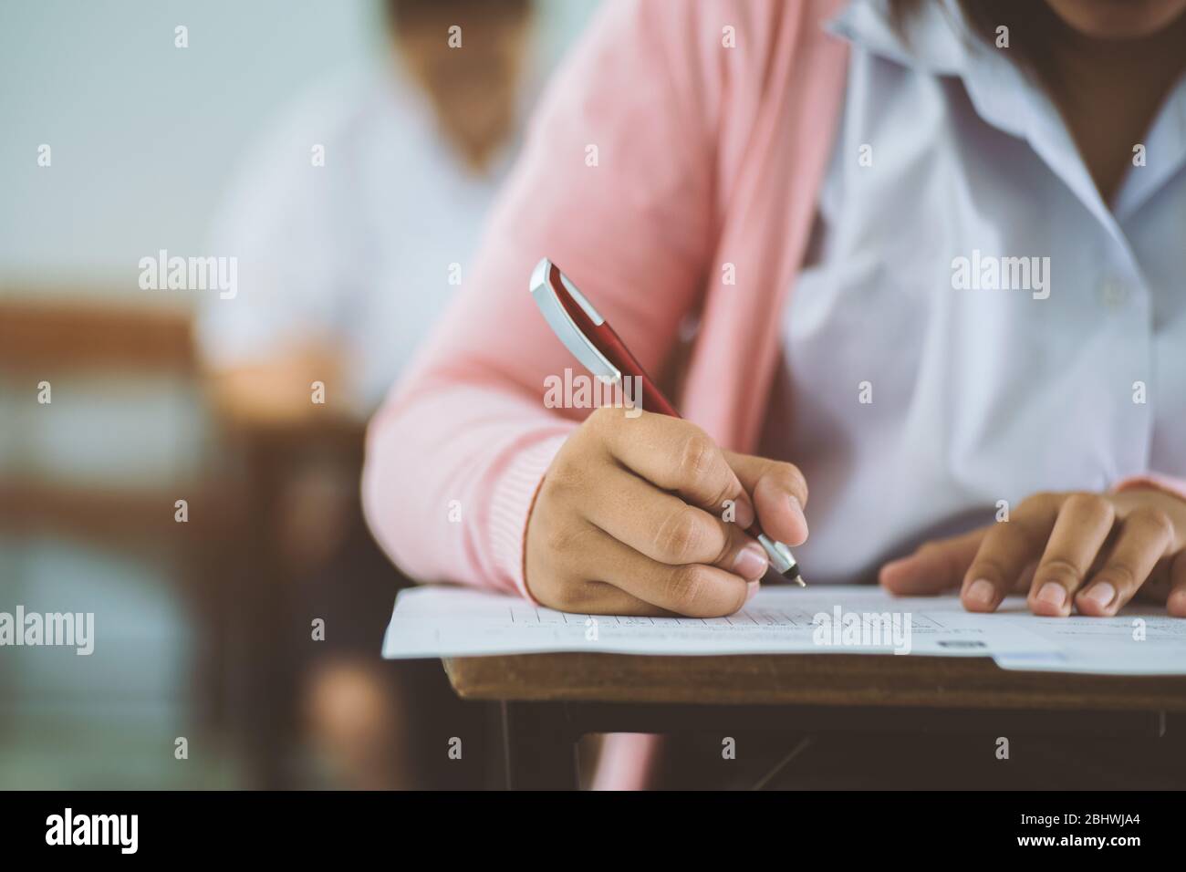 Students writing and reading exam answer sheets exercises in classroom of school with stress. Stock Photo